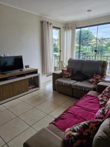 a living room with a couch and a flat screen tv at 1 dorm aconchegante em apto compartilhado com a moradora in Santa Rosa