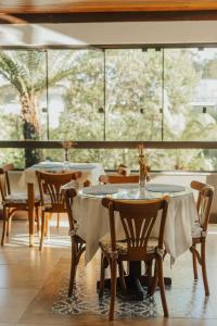 a restaurant with tables and chairs and a large window at Hotel Canto Verde in Gramado