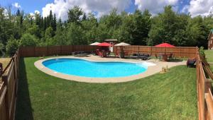 a swimming pool in a yard next to a fence at Suite 2 - Val-Racine in Notre-Dame-Des-Bois