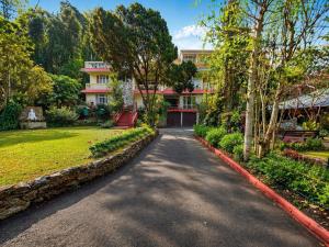 a driveway in front of a building with trees at Shikher Guest House in Kalimpong
