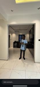 a man standing in a kitchen looking at his cell phone at Love One in Midrand