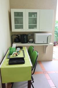 a kitchen with a green table and a microwave at SUITES SANTA FÉcg A5 in Campo Grande