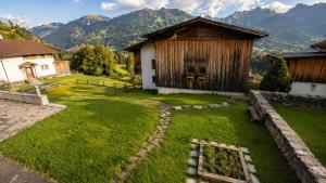 a yard with a small building and mountains in the background at Ferienwohnungen Pez Regina in Lumbrein +2 photos