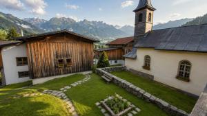 a church with a clock tower and a grass yard at Ferienwohnungen Pez Regina in Lumbrein