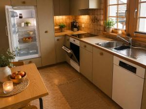 a kitchen with a sink and an open refrigerator at Ferienwohnungen Pez Regina in Lumbrein