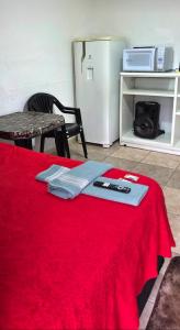 ein Zimmer mit einem Tisch, auf dem eine rote Decke liegt, und einem Kühlschrank in der Unterkunft BSM!o in Caxambu
