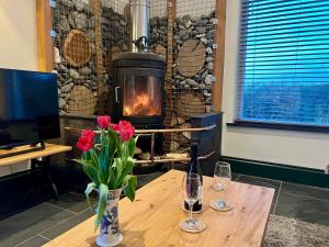 a table with flowers and wine glasses and a fireplace at Loom Cottage, Preseli Venture in Haverfordwest