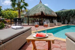 a table with two glasses of wine and a slice of watermelon at Tropical villa Curoyal near the beach in Jan Thiel