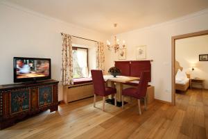 a living room with a dining room table and a television at Ansitz Pünthof in Lagundo +40 photos