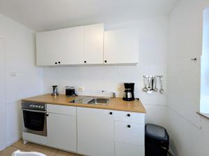a kitchen with white cabinets and a sink at interaktiv Appartements in Heiligenhaus - Herzogstrasse in Heiligenhaus +33 photos