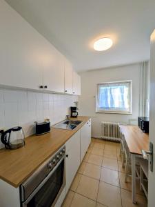 a kitchen with white cabinets and a wooden counter top at interaktiv Appartements in Heiligenhaus - Herzogstrasse in Heiligenhaus
