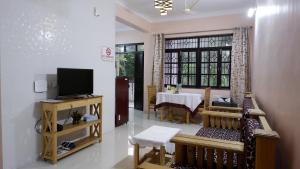 a living room with a television and a dining room at Jasmine Guest House in Majorda