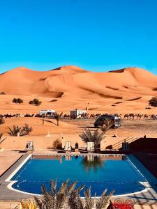 a swimming pool in the middle of a desert at Les Roses Des Dunes in Merzouga