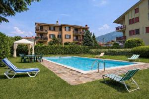 a swimming pool with chairs and a table and a building at SunLake Apartment in Colico