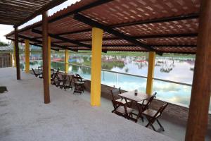 a group of tables and chairs under a pavilion with water at Pousada de Itajuípe em Itajuípe in Itajuípe
