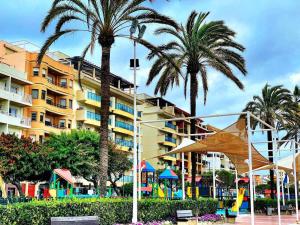 a building with palm trees in front of a playground at Spectacular beachfront apartment in Estepona