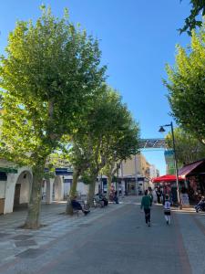 a street with trees and people walking down the street at apartamento en centro in Chipiona