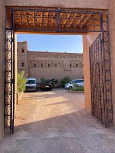 an open gate to a building with cars parked at Auberge Famille Benmoro in Skoura