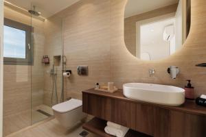 a bathroom with a sink and a toilet and a mirror at Little Crab Suites in Agios Gordios +49 photos