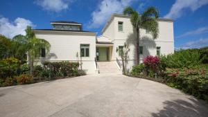 a white house with a palm tree and flowers at Sweet Dreams in Saint James