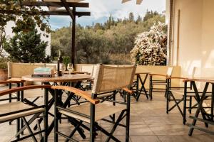 a patio with tables and chairs and a view of trees at Ionion Hotel in Syvota
