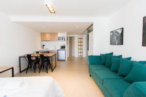 a living room with a green couch and a kitchen at Austral Departamentos in Ushuaia