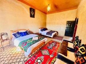 a bedroom with two beds and a rug at Les Roses Des Dunes in Merzouga