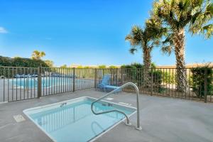 a swimming pool with a chair and palm trees at Seawind Sanctuary in Carolina Beach