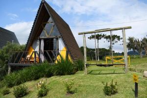 a small house with a gambrel roof and a swing at Chalé Encanto Do Lago in Urubici