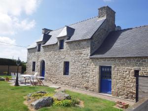 a stone house with a blue door and a table at Gites laurent in Guissény