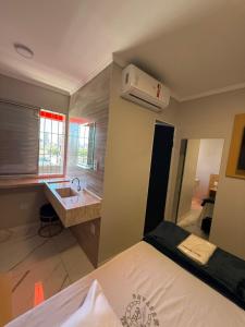 a bedroom with a bed and a sink and a bathroom at Hotel Mustang in São Paulo