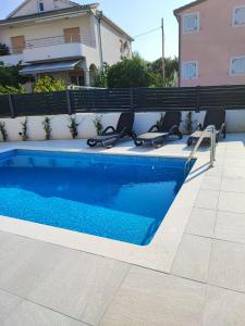 a swimming pool with lounge chairs next to a house at Rusulica Trogir in Seget Vranjica