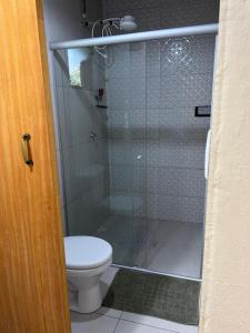 a bathroom with a toilet and a glass shower at Chalé da Janela in Lavras Novas +6 photos