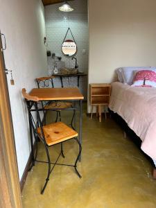 a bedroom with a desk and a bed and a table at Chalé da Janela in Lavras Novas