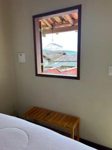 a bedroom with a window and a wooden bench at Chalé da Janela in Lavras Novas