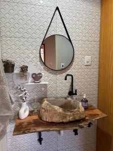 a bathroom with a stone sink and a mirror at Chalé da Janela in Lavras Novas