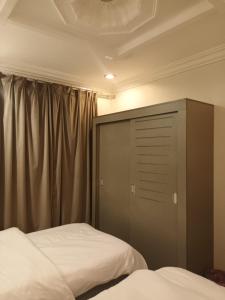a bedroom with a bed and a cabinet and curtains at company petty bark شركة بيتي بارك للشقق المخدومة درجة اقصادية in Qarār