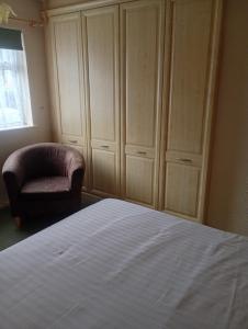 a bedroom with a bed and a chair and a cabinet at IronPig Cottage in Cheadle