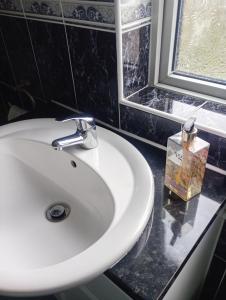 a white sink in a bathroom with a window at IronPig Cottage in Cheadle