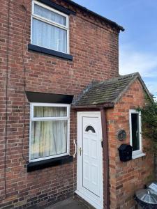 a brick house with a white door and two windows at IronPig Cottage in Cheadle +6 photos