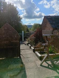 a garden with a bench and a brick building at IronPig Cottage in Cheadle