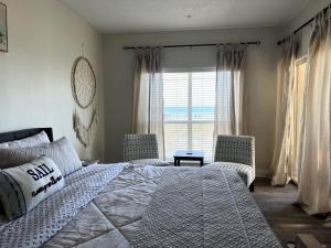 a bedroom with a bed and two chairs and a window at Perdido Key Beachfront 4BR Sleeps 12 Steps to the Beach Sweeping Gulf View in Pensacola