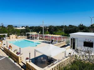 a swimming pool with a tent and a building at Dolce VillaCastelli in Villa Castelli