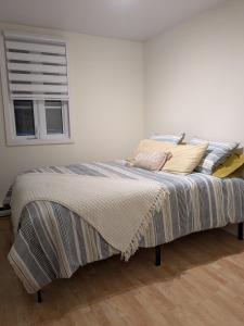 a bedroom with a bed with pillows and a window at La belle ancestrale in Sainte-Anne-des-Monts
