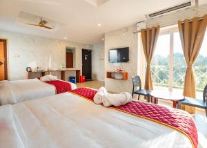 a hotel room with two beds and a tv at White Forest - PV Hotels in Pondicherry