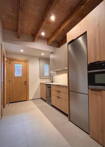 a kitchen with stainless steel appliances and wooden ceilings at La Plana allotjament rural in Aviá