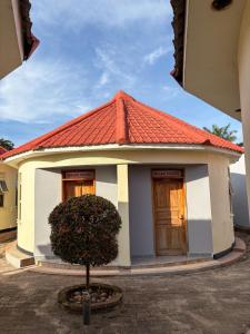 a small house with an orange roof with a tree in front at Wilna Motel Garuga in Kagolomolo