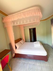 a bedroom with a bed with a canopy at Wilna Motel Garuga in Kagolomolo