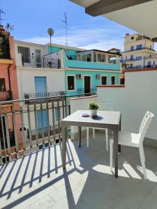 a table and a chair on a balcony with buildings at M&C Home in Letojanni