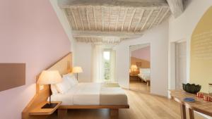 a white bedroom with a bed and a mirror at Mastrojanni Relais - Small Luxury Hotels of The World in Montalcino +53 photos